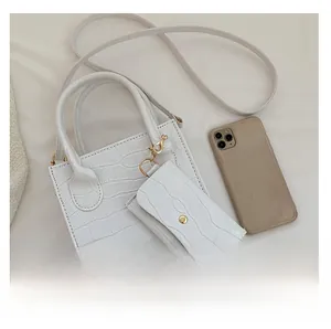 Detailansicht der weißen Tasche mit Krokodilprägung, kleinem Beutel und goldener Hardware