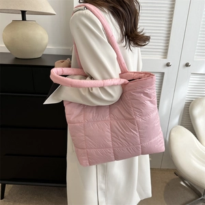 Pink quilted puffer tote bag with padded straps shown in a modern home interior setting