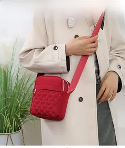 Red quilted nylon crossbody bag shown with a beige coat in a stylish casual setting