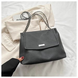Detailed shot of black leather handbag featuring silver metal buckle and chain strap