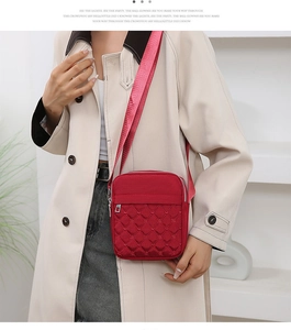 Detail of red quilted oxford crossbody bag with silver zippers and wide nylon strap