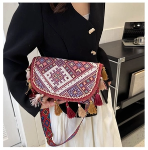 Close-up of bohemian embroidered crossbody bag with colorful tassels and jacquard strap