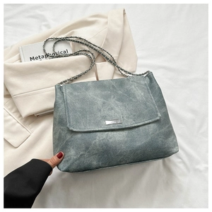 Detail of gray-blue chain shoulder bag with metal logo on a stylish neutral background