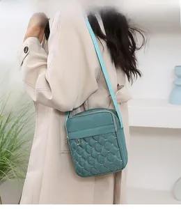 Detail of green nylon crossbody bag with star embroidery on a minimalist trench coat