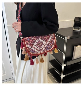 Detail of ethnic embroidered crossbody bag with long tassels and woven geometric strap