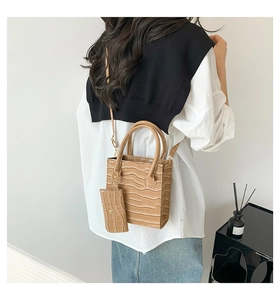 Detail einer hellbraunen quadratischen Handtasche mit Kroko-Muster und kleinem Etui