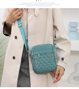 Detail of teal quilted crossbody bag with star embroidery and adjustable strap