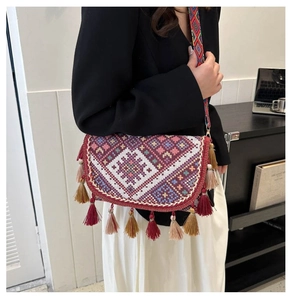 Close-up of geometric ethnic embroidery and colorful tassel trim on the shoulder bag