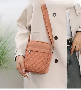 Close-up of quilted orange-pink nylon crossbody bag showing the rhombus stitch texture