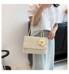 Detailed view of cream woven tote bag with yellow floral ornament and rope straps