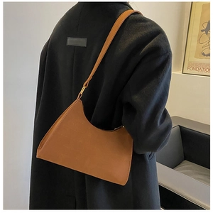 Detail view of brown matte leather baguette hobo bag with round gold metal buckle