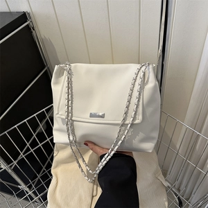 Minimalist white leather chain shoulder bag with silver metal tag in a shopping scene