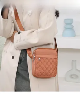 Close-up of caramel quilted oxford small crossbody bag worn with a beige trench coat