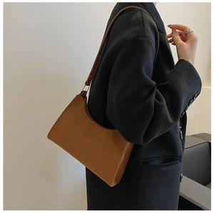 Brown matte baguette shoulder bag worn over a black wool coat for a chic winter look