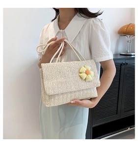 Macro shot of ivory woven straw handbag featuring a handcrafted yellow fabric flower detail