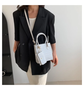 Weiße Handtasche mit Krokodilprägung und goldenen Details getragen von einem Model im Studio