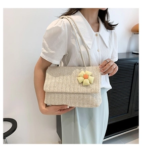Detail of beige woven straw shoulder bag featuring a 3D plaid flower and rope straps