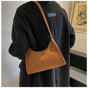 Brown frosted leather hobo bag with gold hardware shown on a model in a black wool coat