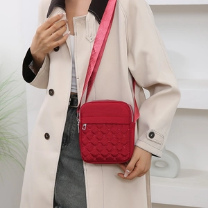 Minimalist red quilted nylon crossbody bag with adjustable strap shown on model