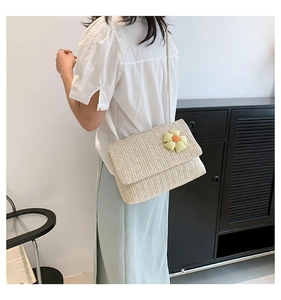 Close-up of beige woven shoulder bag featuring delicate yellow and orange floral embroidery