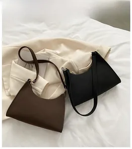 Detail view of retro baguette underarm bags in dark brown faux leather and black textures