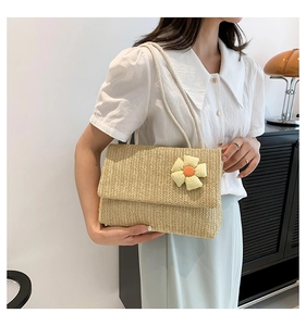 Detail of hand-woven straw tote bag with yellow checkered floral accent and slim straps