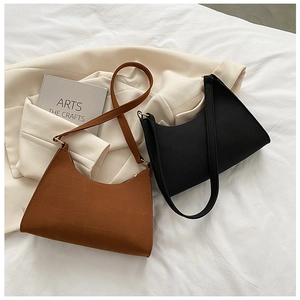 Close-up of minimalist brown crocodile pattern and matte black leather underarm bags