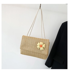 Detail of woven straw shoulder bag featuring a yellow checkered fabric flower decor
