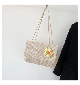 Detail of woven beige tote bag with a small yellow plaid floral ornament on white background