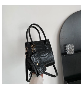 Detailansicht der schwarzen Kroko-Handtasche mit goldener Hardware und kleiner Tasche