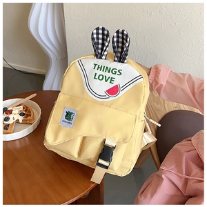 Detail of yellow school backpack with rabbit ears and cute watermelon pattern design