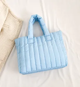 Detail of light blue puffer tote bag featuring vertical quilted texture and soft handles