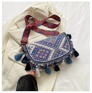 Detail of ethnic style crossbody bag with geometric weave, colorful tassels and wide strap