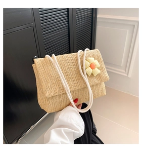 Detail of hand-woven straw shoulder bag with cotton rope strap and flower decor