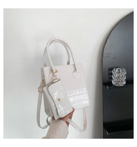 Detail der weißen Handtasche mit Krokodilprägung, verstellbarem Gurt und Goldbeschlägen