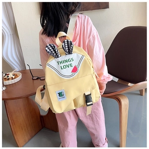 Detail of yellow canvas backpack with rabbit ears and adjustable shoulder straps