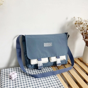 Detail view of canvas messenger bag with dual front pockets on a wooden bench