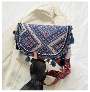 Detail of bohemian crossbody bag showing colorful geometric weaving and ethnic blue tassels