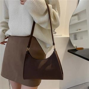 Minimalist chocolate brown hobo underarm bag with gold hardware on a stylish model