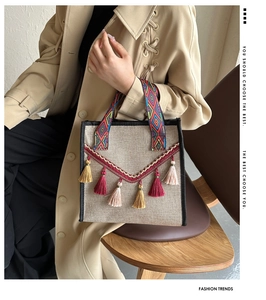 Détail du sac seau en lin ethnique avec pompons colorés et poignée tissée en situation