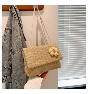 Detail of woven straw tote bag with yellow checkered flower and white rope straps