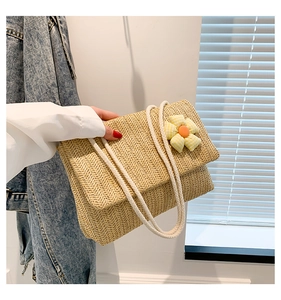 Close-up of woven straw tote bag featuring detailed texture and a yellow plaid floral ornament