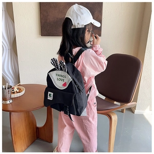 Detail of cute rabbit ears and watermelon patch on a black canvas kids backpack