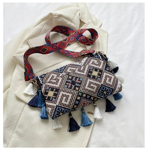 Detail view of ethnic crossbody bag with colorful tassels and wide patterned strap