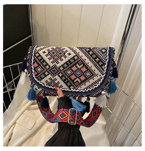 Detail of bohemian ethnic woven crossbody bag featuring colorful tassels and wide strap