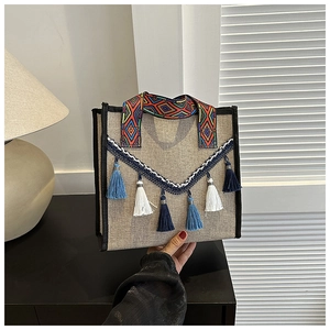 Détail d'un sac seau en lin bohème avec glands ethniques et bandoulière géométrique colorée