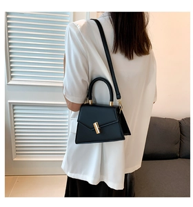 Détail d'un sac à main noir minimaliste en cuir avec fermoir doré et bandoulière réglable