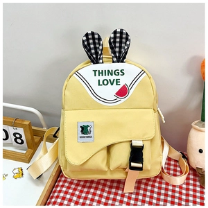 Detailed view of yellow children's backpack with rabbit ears and cute bear patch