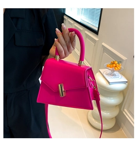 Detail of rose red leather handbag featuring gold twist lock and sturdy round handle