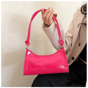 Detail of fuchsia crocodile pattern leather shoulder bag with decorative knotted strap